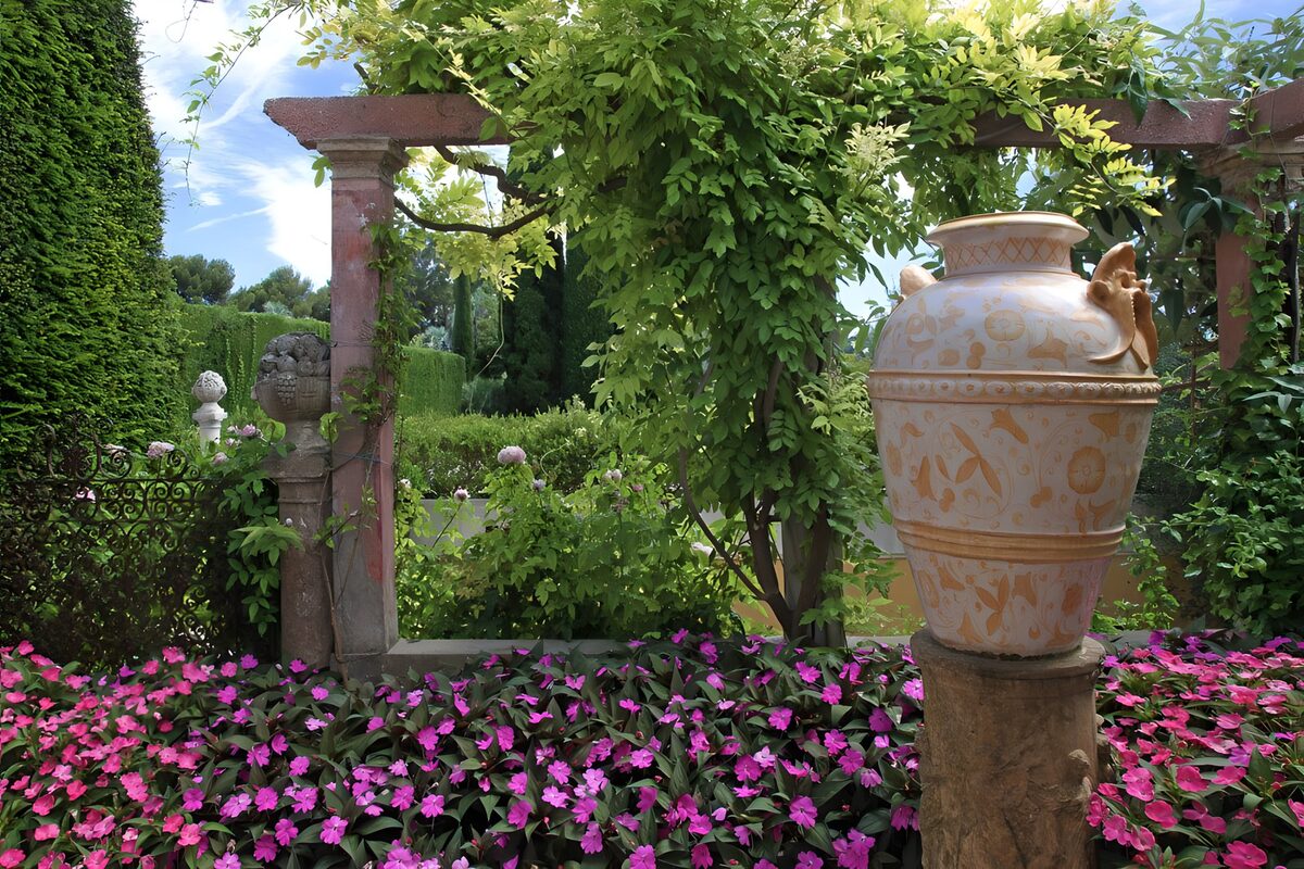 Jardín con flores rosas y una gran urna