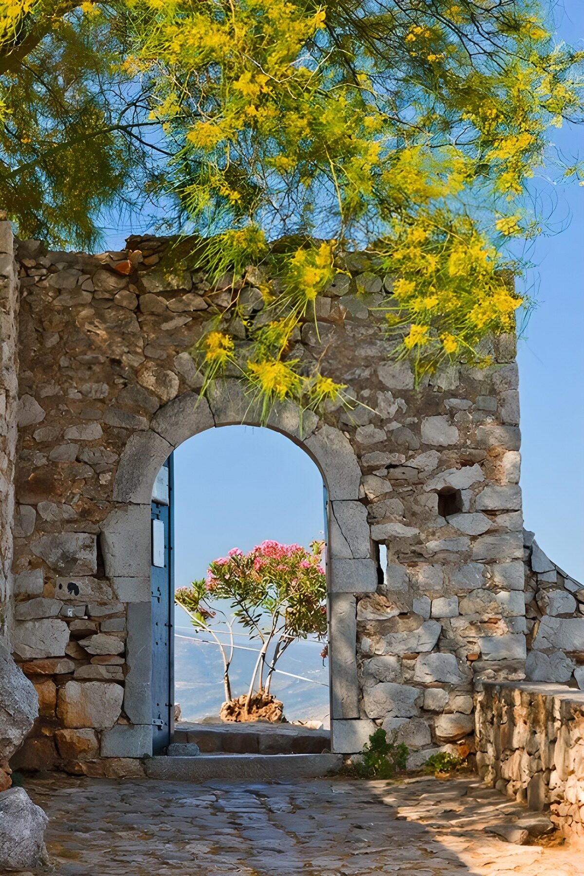 Arco de piedra entre flores y montañas