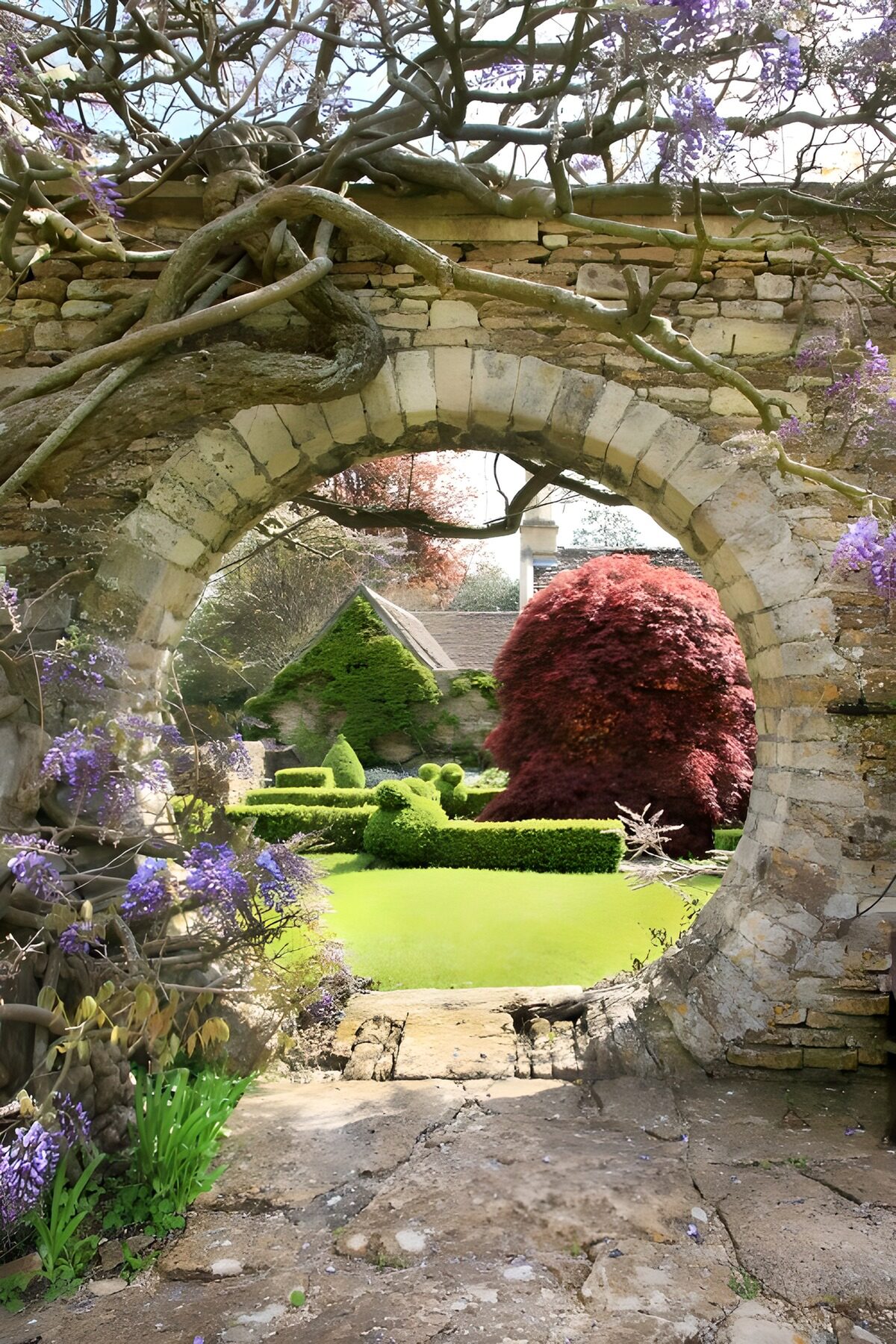 Arco de piedra y glicinias al sol