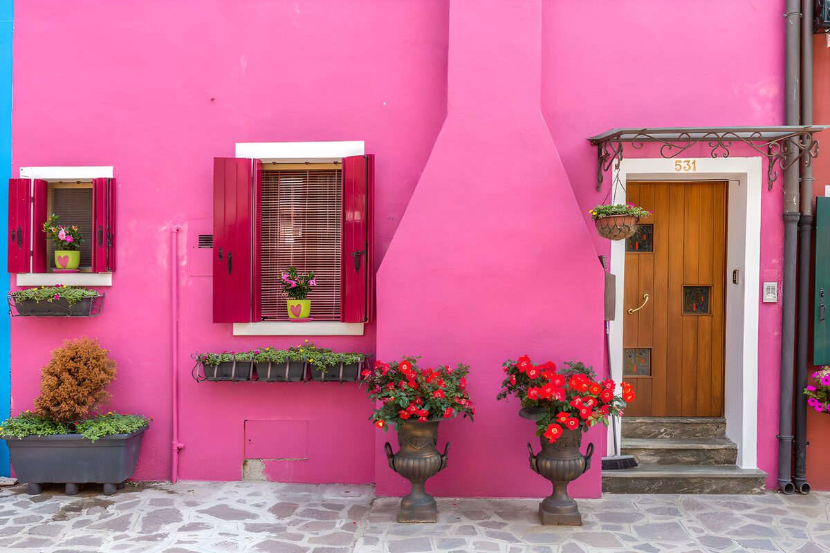 Fachada fucsia con flores de bienvenida
