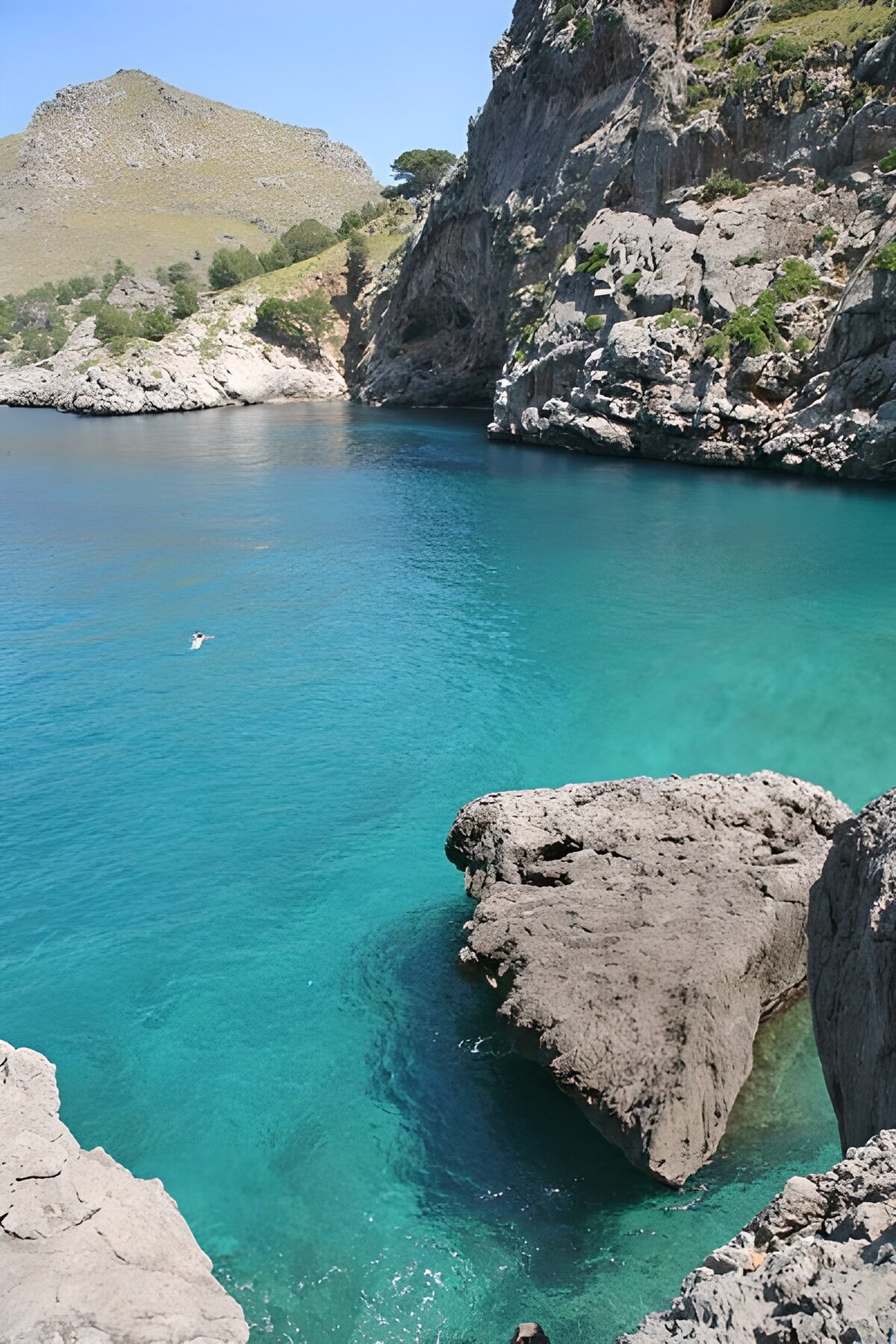 Cala turquesa entre rocas al sol