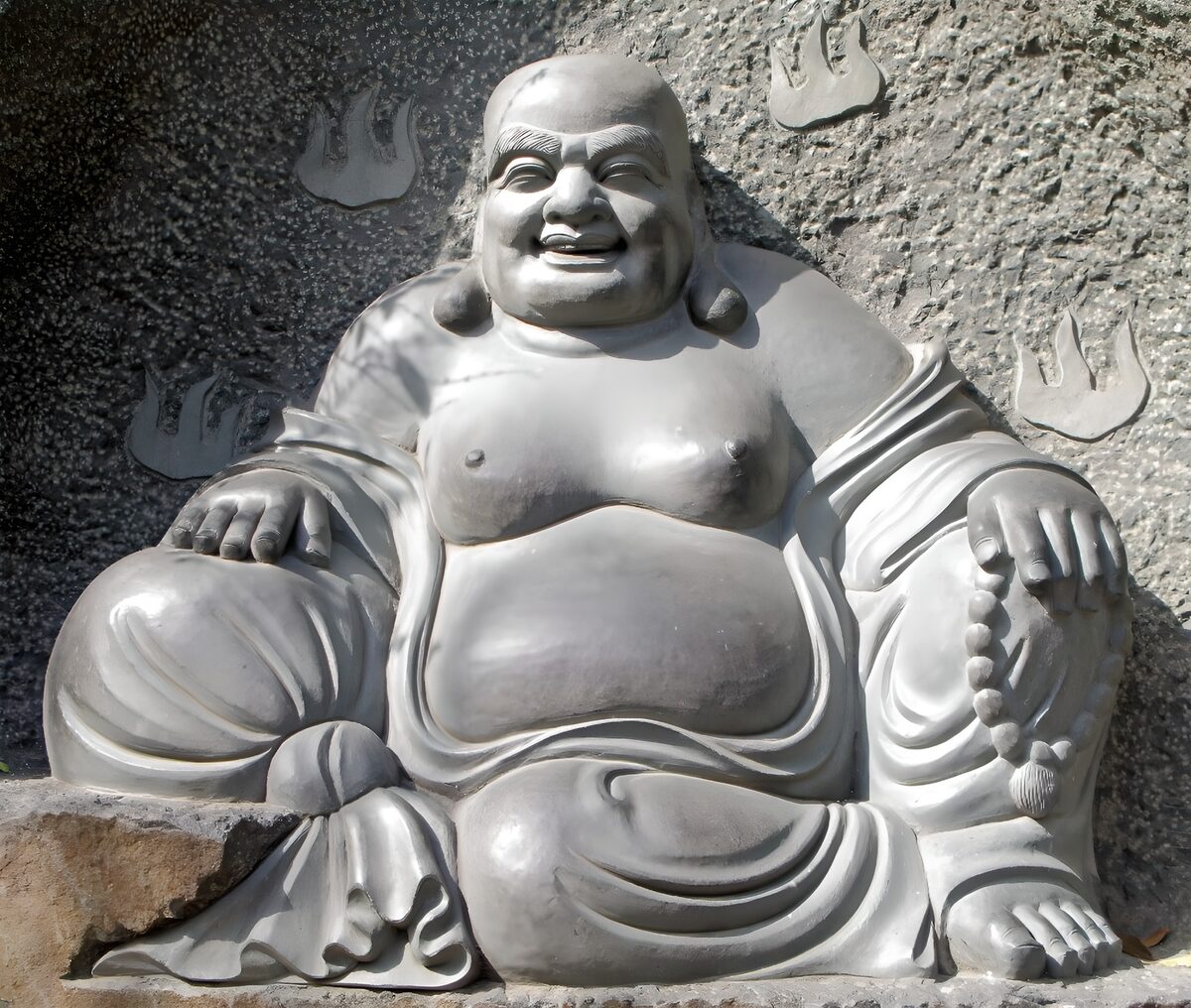 Buda sonriente de piedra al sol