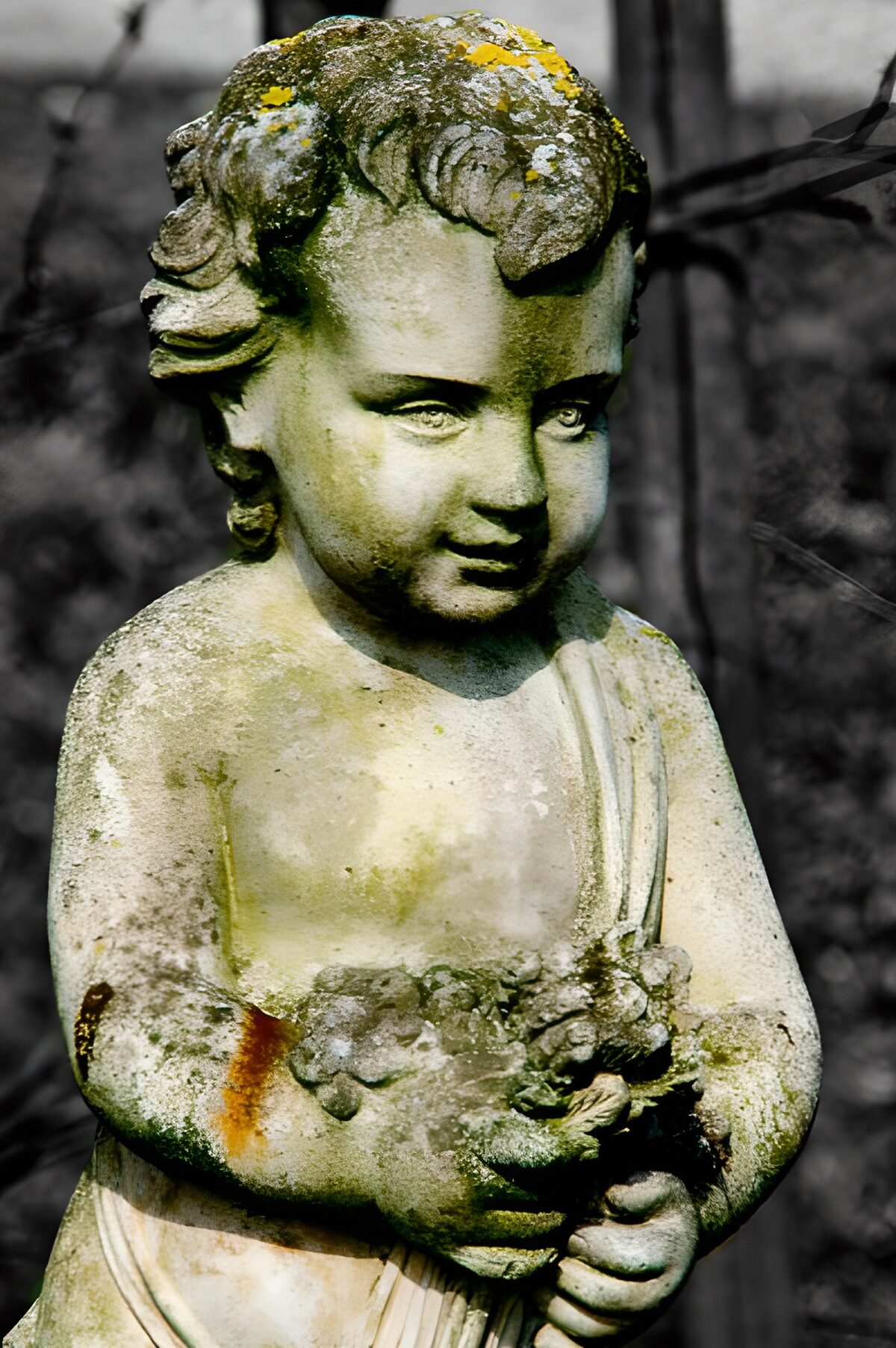 Niño de piedra con flores y mirada baja