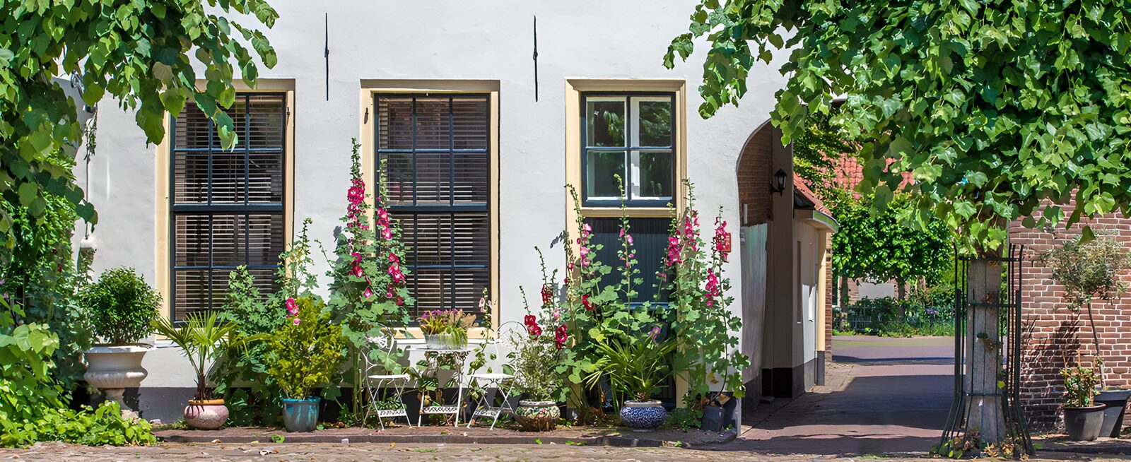 TPES88527: Fachada blanca con flores y sillas al sol