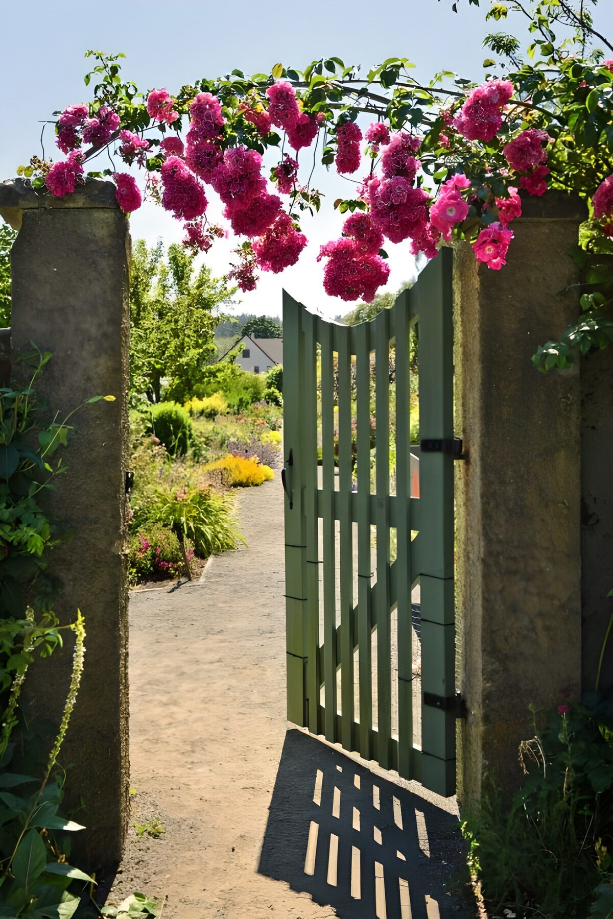 Puerta verde abierta entre flores rosas