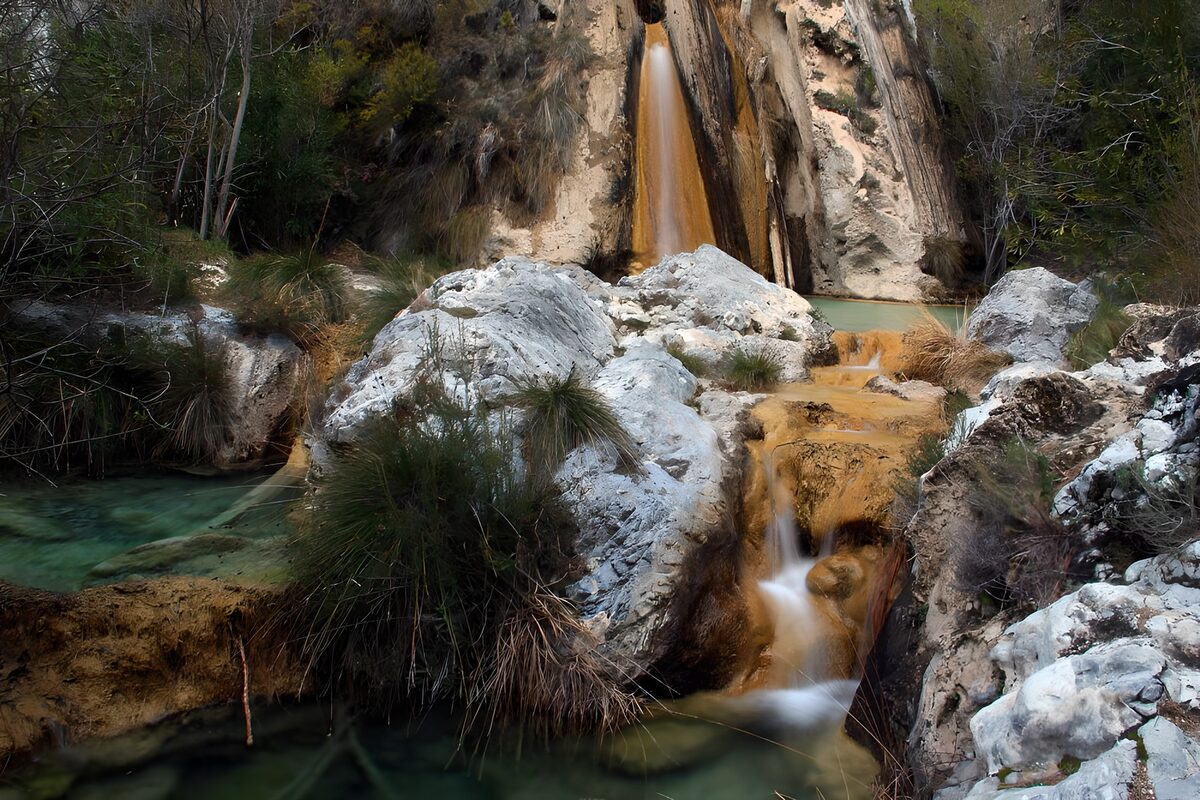 Cascada y pozas verdes entre sombras