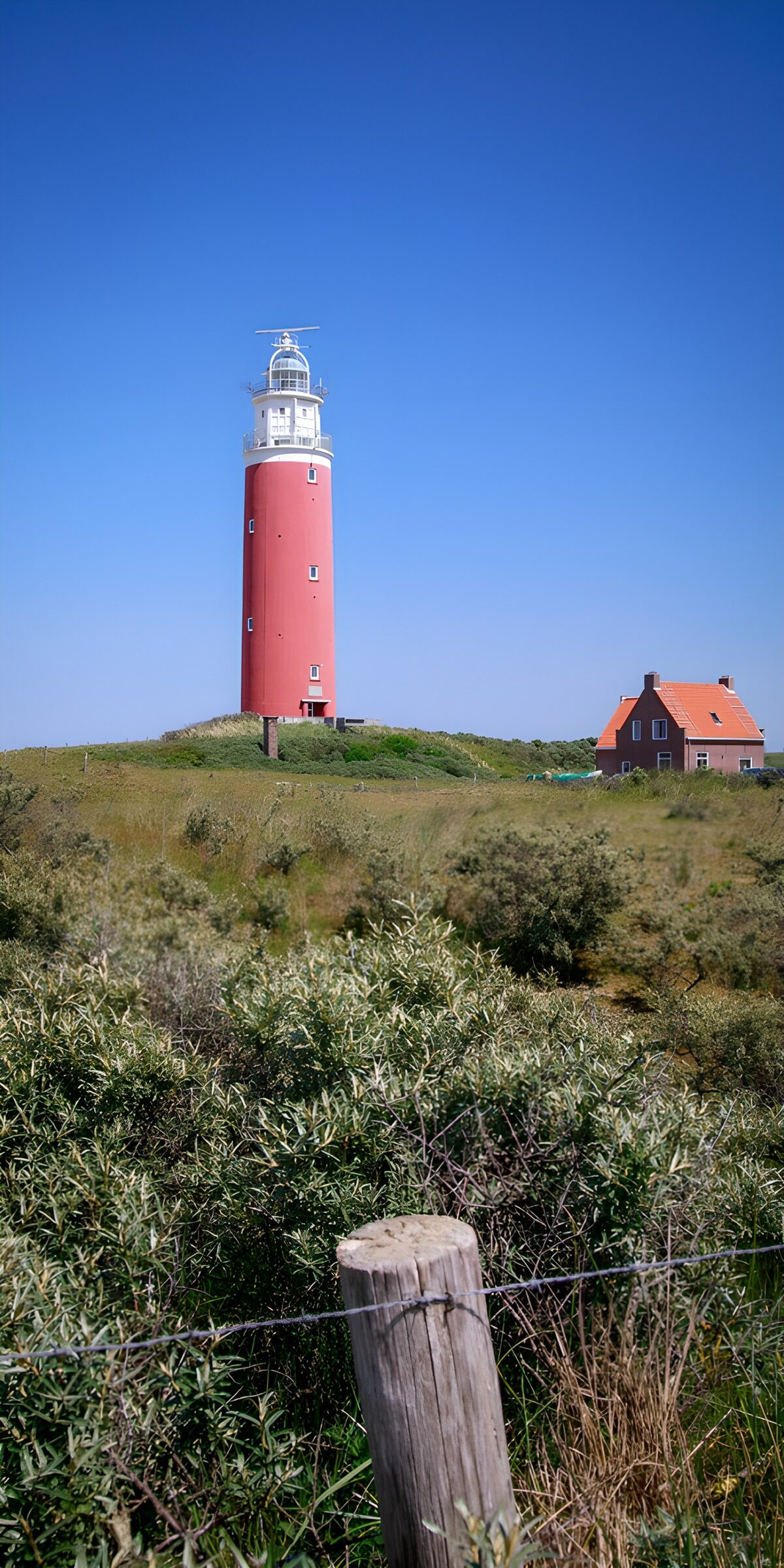 TPES41669: Faro rojo entre dunas bajo un cielo azul