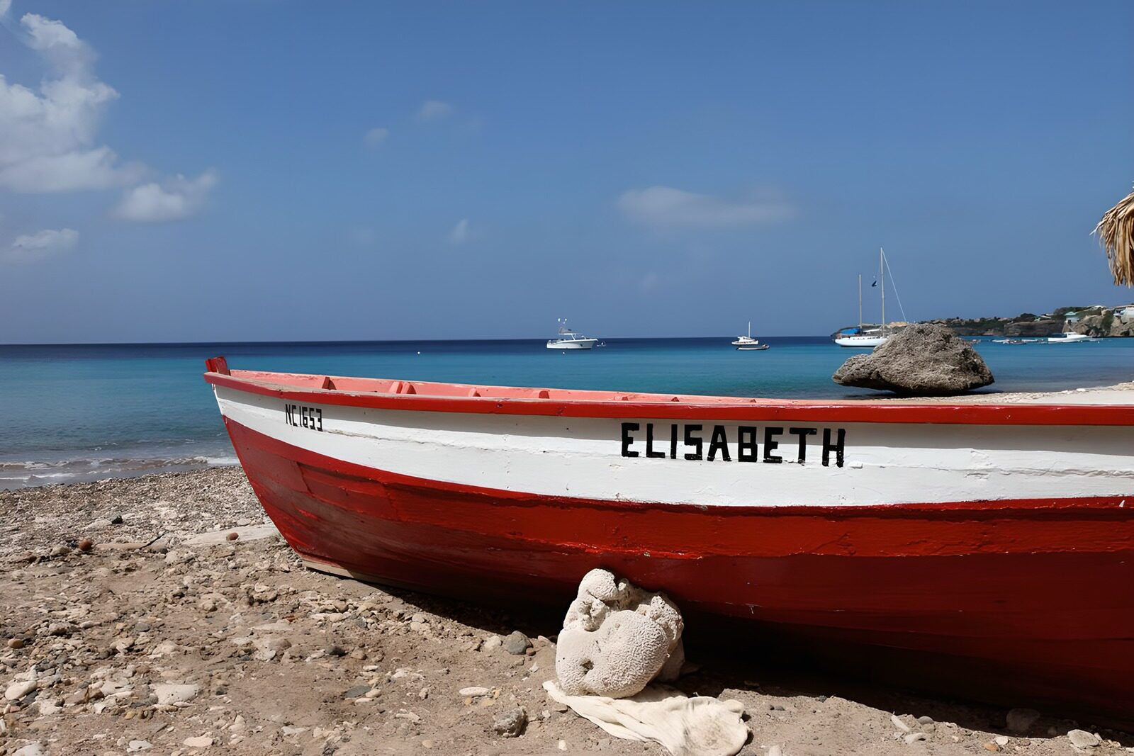 TPES57206: Barca roja al sol en la playa de piedras