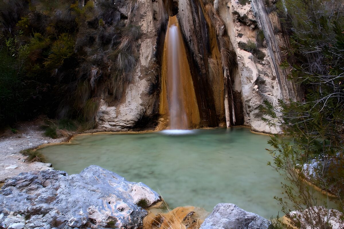 Cascada entre rocas y una poza en calma