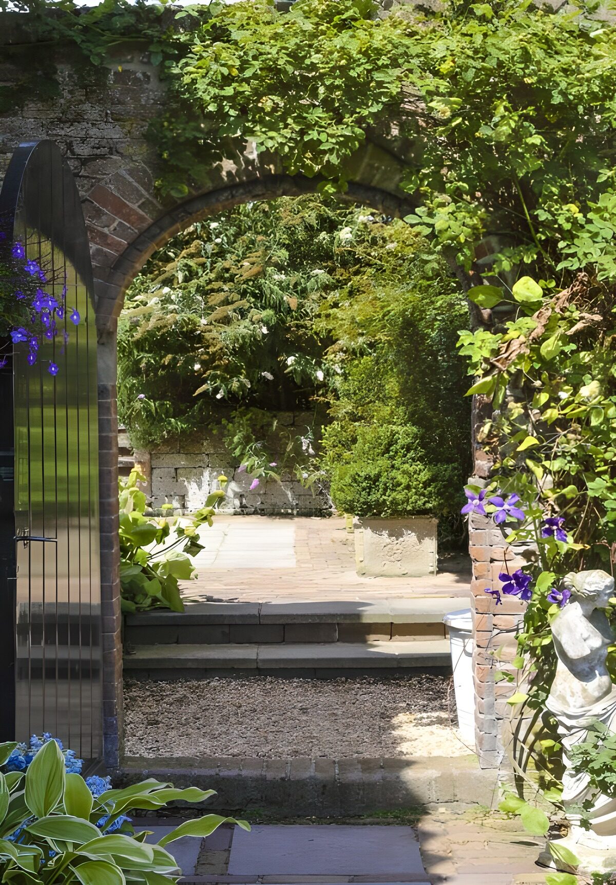 Arco de piedra hacia un jardín en sombra