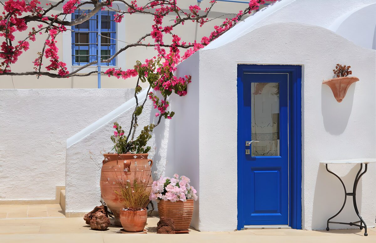 Patio al sol con puerta azul y buganvilla