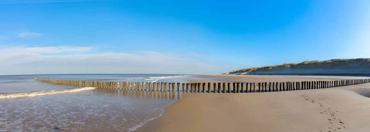 Playa con espigones de madera y mar en calma