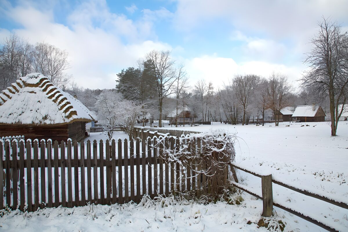 Cabaña y valla de madera bajo la nieve