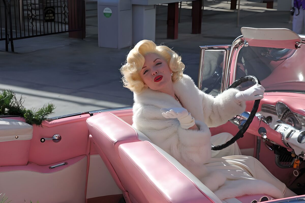 Rubia con abrigo blanco en coche rosa