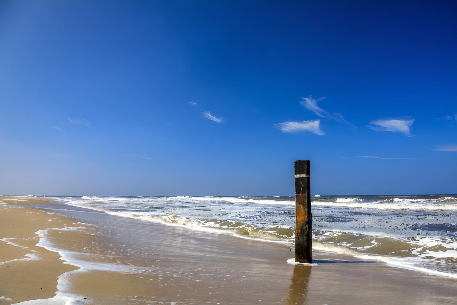 TPES45634: Playa de arena y un poste entre las olas