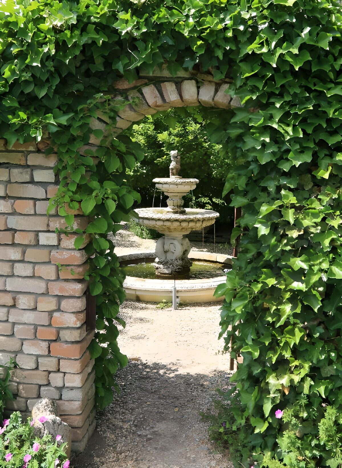Fuente bajo un arco de ladrillo y hiedra