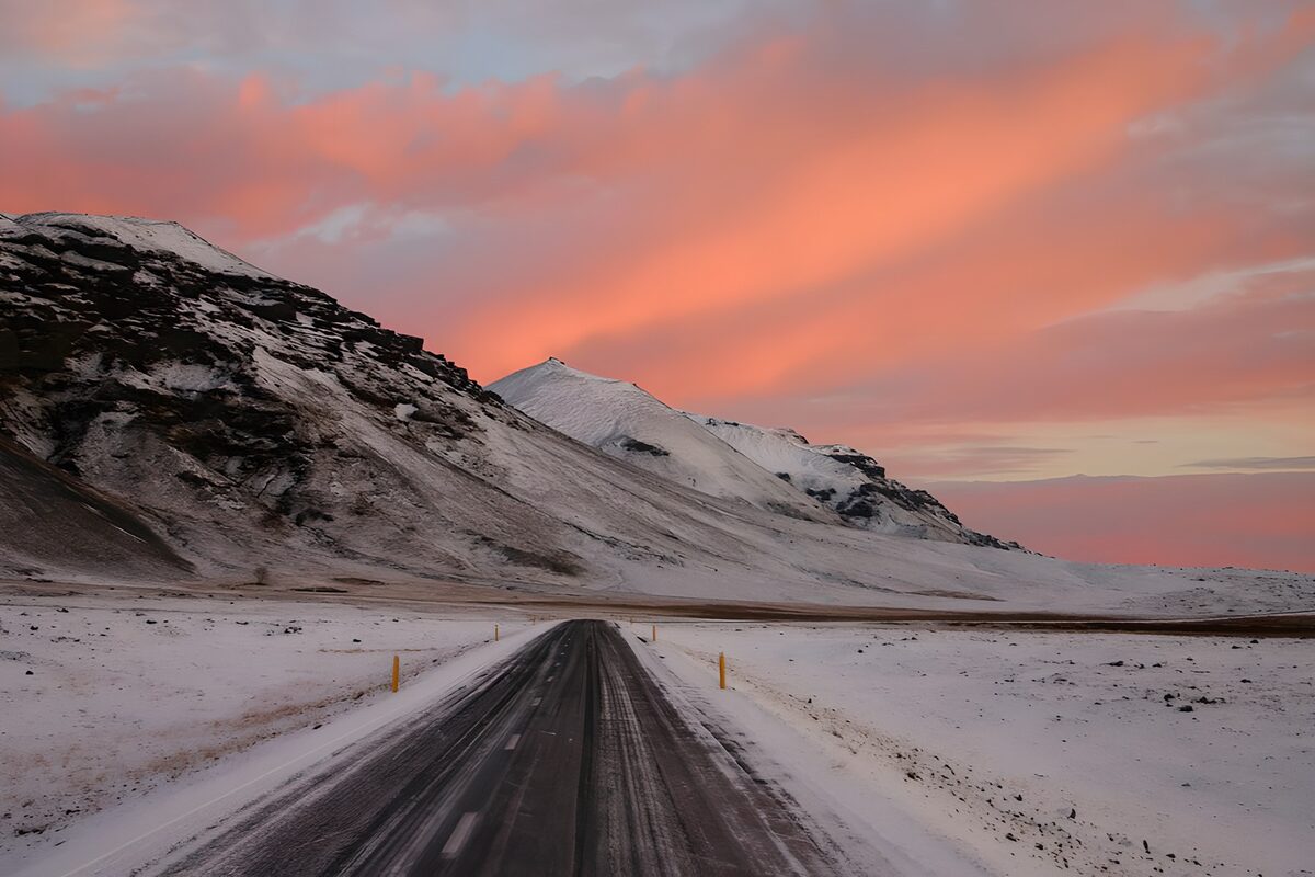 Carretera nevada bajo un cielo rosa