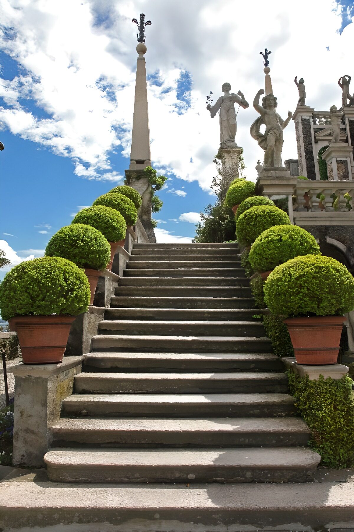 Escalera de piedra entre macetas y estatuas