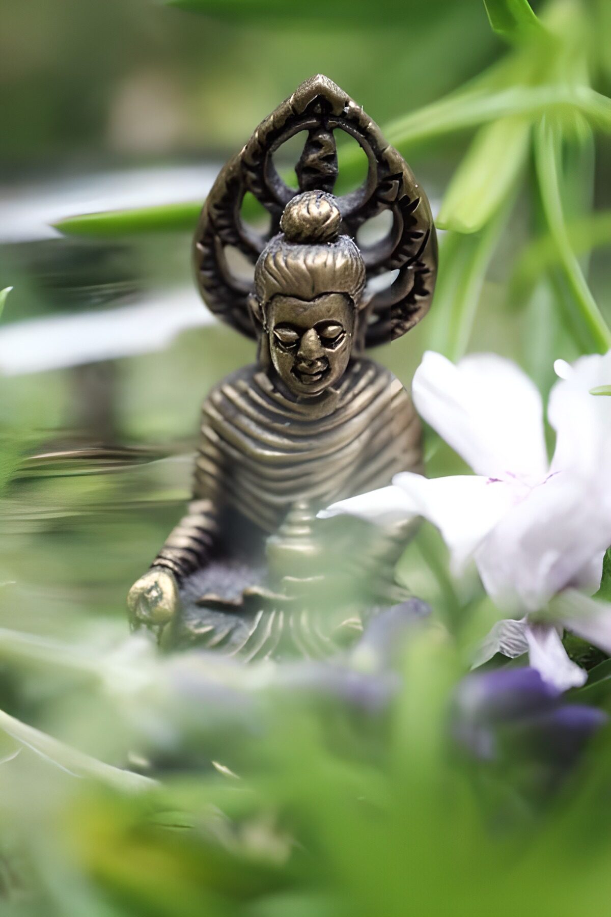 Buda de bronce junto a una flor blanca