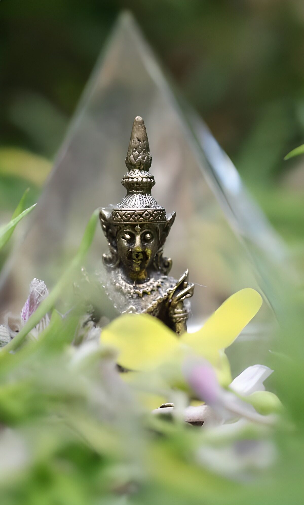 Buda de bronce entre hojas y flores